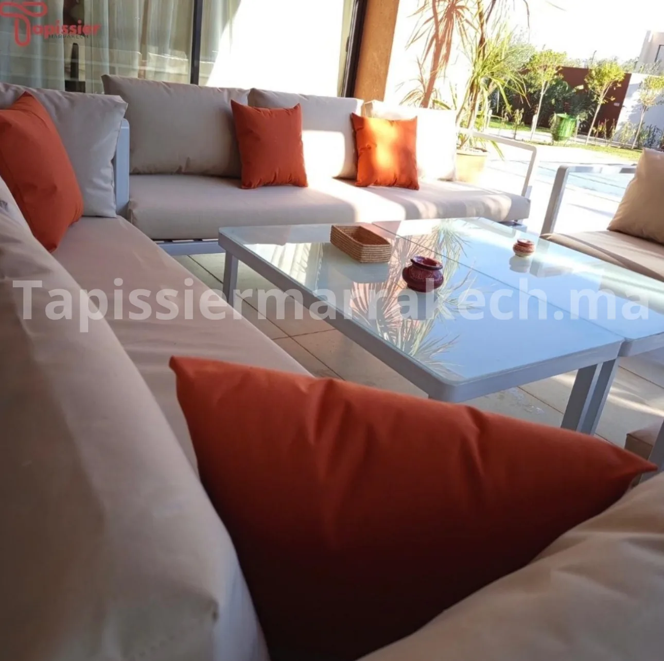 Canapé extérieur blanc avec coussins orange et table basse bleue